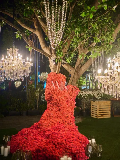 A unique floral sculpture of a couple embracing, made entirely of red flowers. This artistic piece was a central feature of the decor, surrounded by candles and chandeliers hanging from the trees.