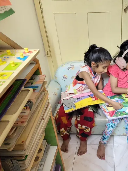 Two little friends sharing a book on a cozy chair. Reading together helps build early literacy skills and, more importantly, beautiful friendships.