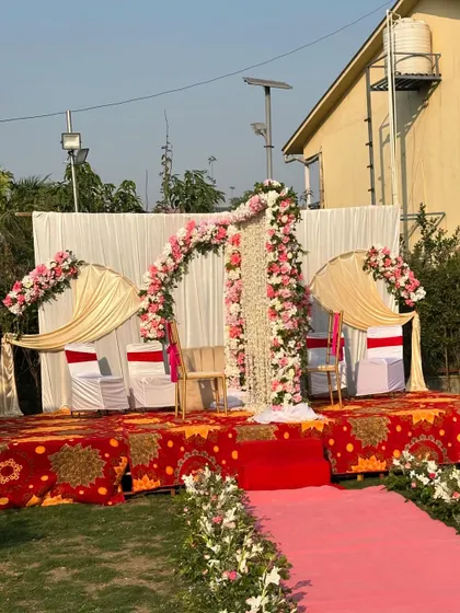 A beautiful outdoor Nikah partition setup for a daytime ceremony. The stage is decorated with a floral arch of pink and white roses and a central partition of hanging white flowers.