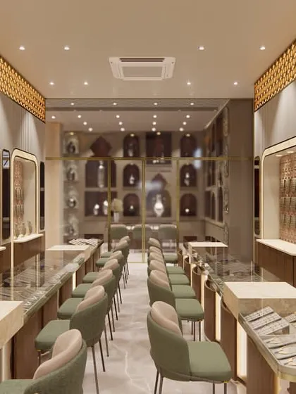 A perspective shot of the redesigned jewellery showroom, showing the flow between different counter sections. The combination of warm wood tones, green velvet chairs, and intricate gold-toned ceiling details creates a cohesive and luxurious atmosphere.