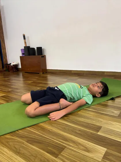 A young boy relaxes in Supta Baddha Konasana, or Reclined Butterfly Pose, a great restorative pose for opening the hips.