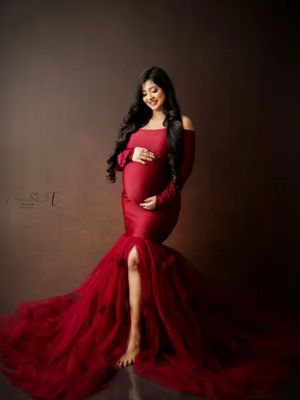 A stunning portrait in a rich red gown. The off-the-shoulder design and tulle skirt create a glamorous and elegant look.