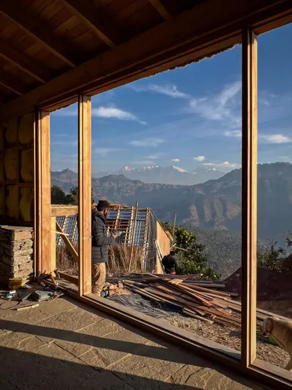 Looking out from a nearly completed guesthouse in Vasudev. The large wooden window frames are designed to capture the panoramic views of the Nanda Devi and Panchachuli peaks, making the landscape the main feature of the room.