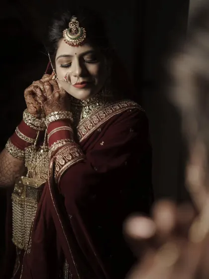 A quiet moment during the getting-ready process. The soft lighting and the bride's focused expression as she puts on her earrings create an intimate and beautiful portrait.