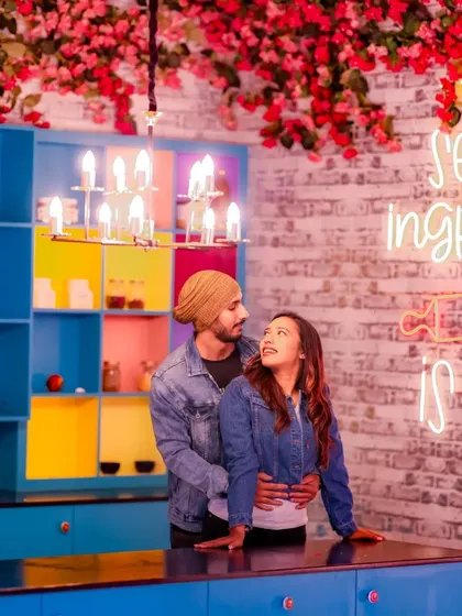 A beautiful shot of a couple in a quirky kitchen, with a neon sign adding a romantic glow. This is a great example of a creative and modern pre-wedding shoot.