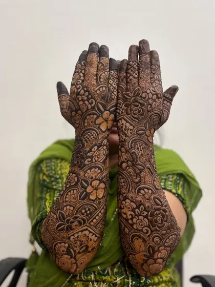 A shy bride showing off her full bridal mehndi. The design is rich with traditional patterns.