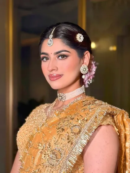 A close-up portrait showcasing the flawless makeup and the delicate hair accessories that complete this luxurious golden bridal style.