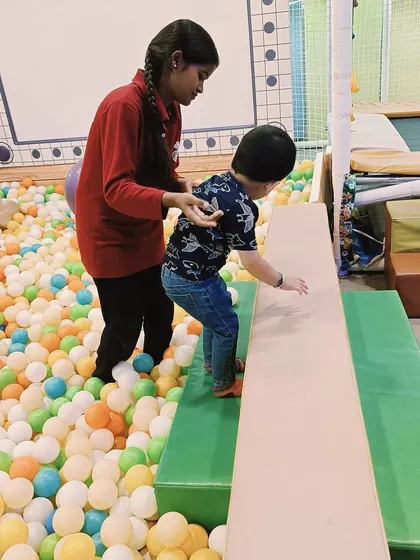 A toddler carefully walks across a balance beam next to a colorful ball pit at our Ashok Vihar center. This activity is excellent for developing balance and focus, with a soft landing nearby to encourage risk-taking.