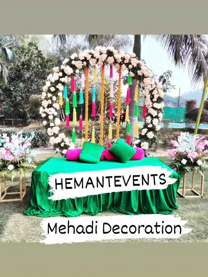 This is a simple and fresh outdoor Mehendi seating area. I used a green velvet-covered divan with a colorful floral arch backdrop, perfect for a garden or farmhouse event.