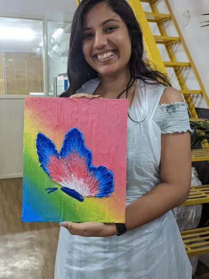 A participant with her vibrant butterfly texture painting. The rainbow gradient background makes the textured butterfly stand out beautifully.