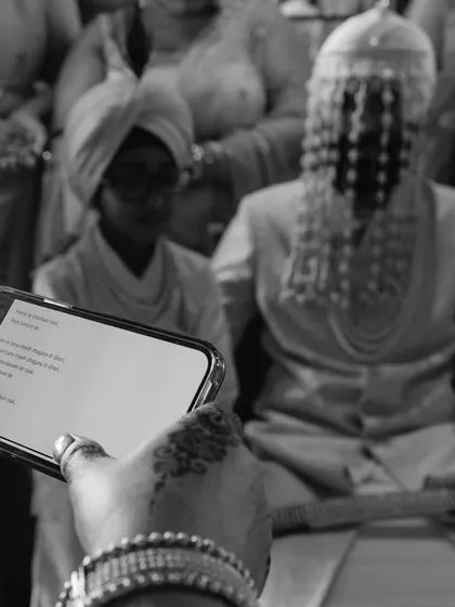A modern twist on tradition. A guest reads the prayers from a phone during a traditional ceremony, a candid moment I love to capture.