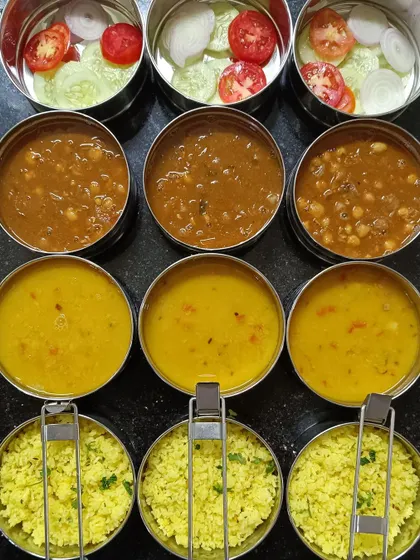 Packing in full swing. This image captures the process of portioning out lemon rice, dal, chana masala, and salad into individual bowls for my subscribers.