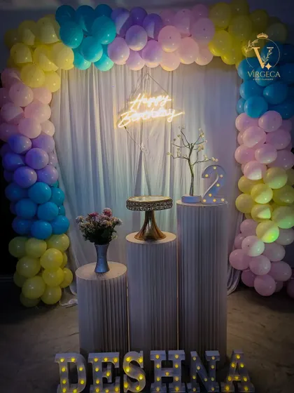 A pastel rainbow-themed birthday party. The soft colors of the balloon arch create a dreamy and gentle atmosphere.