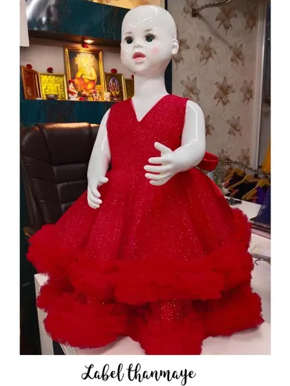 A bright red customized gown with a shimmery fabric and a fluffy, layered hem.
