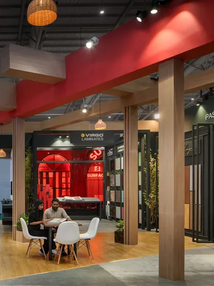 This interior view of the Virgo pavilion shows how the overhead structural elements and pillars define the space. The combination of wood textures and red accents creates a cohesive and branded environment for meetings and product displays.