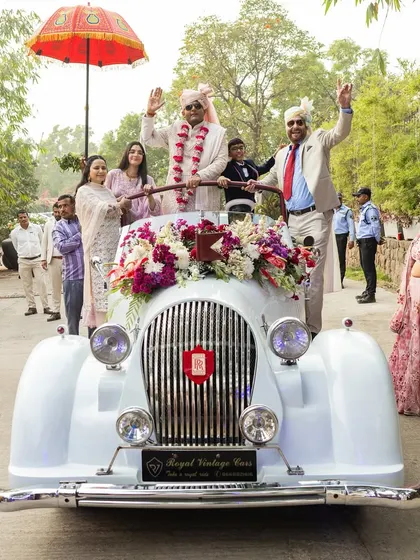 A classic groom's entry in a vintage white Rolls-Royce, a timeless and elegant choice for a grand arrival.