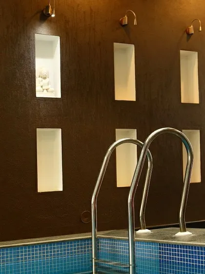 A detail of the indoor pool area in the Courtyard Home. The textured wall features recessed niches for ambient lighting and decor, adding a layer of refinement to the space.