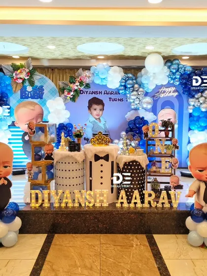 A grand Boss Baby setup for Diyansh Aarav's first birthday. This decor features blue and silver balloons, a personalized backdrop with the birthday boy's photo, and multiple character cutouts.