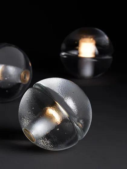 Three clear glass 14p lamps are arranged together, showcasing the slight variations that result from the hand-poured glass process.