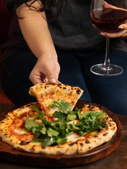 An ode to hands and food. A simple slice of pizza, enjoyed with a glass of wine, becomes a sublime dance of textures and flavors.