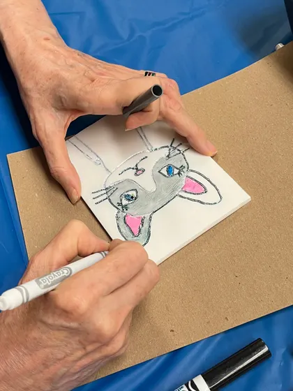 An adult participant drawing a cute cat for her printmaking design. Our workshops are a great activity for both kids and adults to enjoy together.