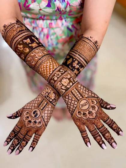 A crossed-hands pose showcasing the symmetry and detail of this baby shower henna art.