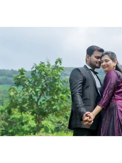 A romantic pre-wedding portrait in a lush, green landscape. The couple holds hands, their connection evident against the beautiful natural scenery.