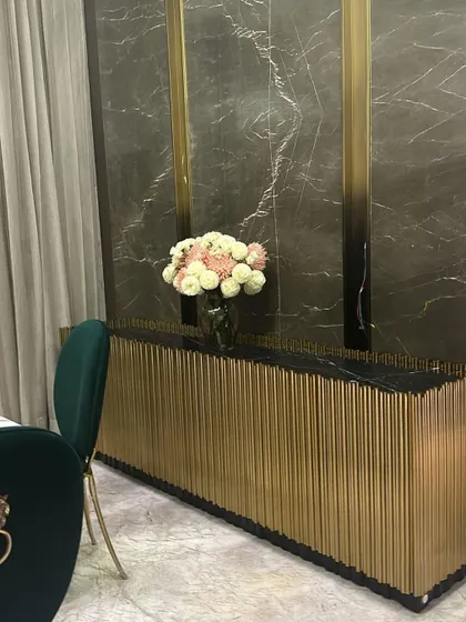 A close-up of our opulent sideboard with a facade of vertical gold tubes, creating a stunning visual texture in this client's dining room.