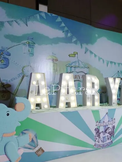 A personalized name display with large marquee letters for 'AARYAV', set against a whimsical carnival-themed backdrop.