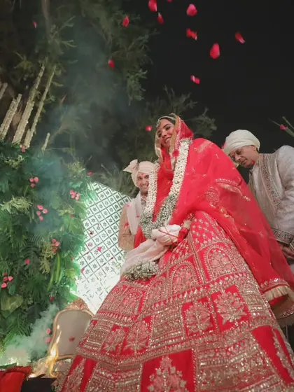 A low-angle shot of the jaimala or garland exchange ceremony. The shower of rose petals adds a sense of celebration and grandeur to this important ritual.