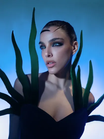 A beauty-focused shot that highlights the unique styling and the model's striking features under cool, directional lighting.