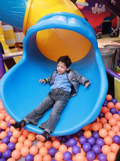 Ready, set, slide. This young explorer is about to launch into our vibrant ball pit, showcasing one of the most loved activities at our indoor playground.