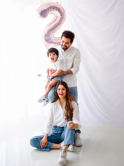 A fun and dynamic family pose. This "family totem pole" is a great way to capture a playful moment, celebrating their son's second birthday with a number 2 balloon.