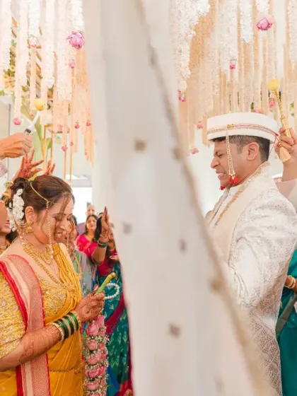 The cloth is dropped, and the couple sees each other, smiling, during the Marathi wedding ceremony. This is a moment of pure joy and the official start of their union.