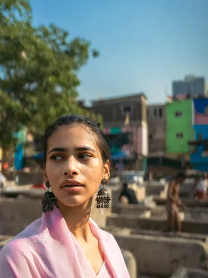 A profile shot looking away from the camera, giving a sense of being lost in thought amidst the daily work of the ghat.