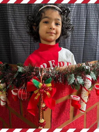 A child peeks out of a Christmas sleigh prop, full of holiday cheer. Our themed photo booths make celebrations extra special and fun.