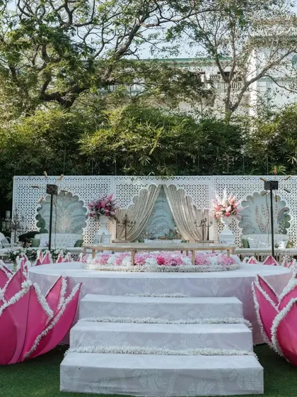 A full view of the Lotus Mandap stage, flanked by large, illuminated lotus flower installations. The all-white stage creates a serene and pure platform for the sacred ceremony.