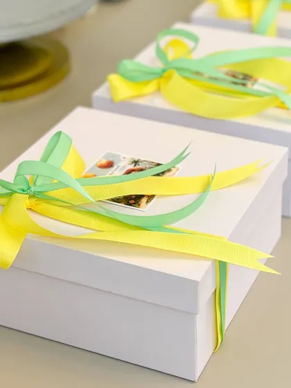 We love adding a pop of color to our Rakhi gifts. These simple white boxes are brightened up with cheerful yellow and green ribbons.