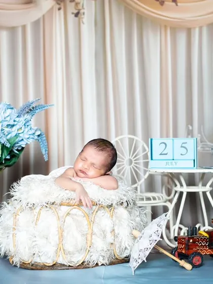 A beautiful, dreamy setup with a newborn sleeping in a basket, with a date block marking their birthday.