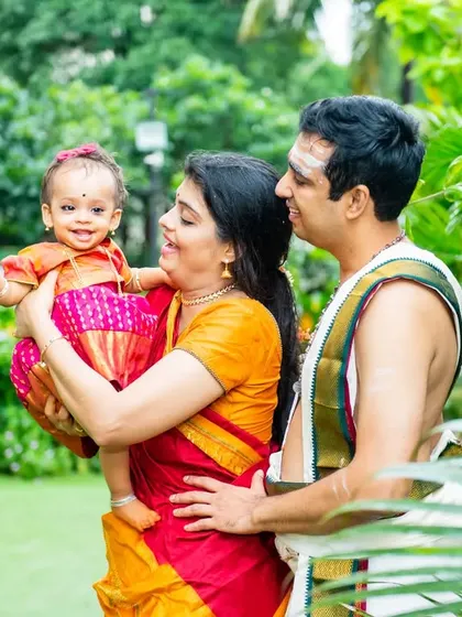 Capturing the joy of an Ayusha Homam ceremony. This outdoor shot shows the family in traditional South Indian attire, celebrating their child's milestone with smiles and laughter.