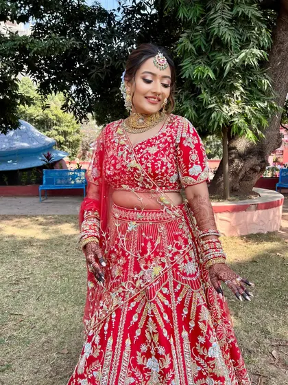 A full-length shot of the bride in an outdoor setting, looking joyful and radiant in her red lehenga.
