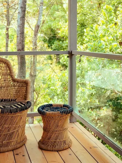 A cozy wicker chair and table on a private balcony, offering a perfect spot to enjoy the forest view.