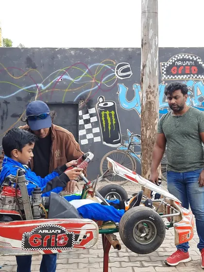 A young driver learning about his kart from a coach.
