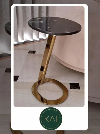 A sleek and modern side table with a black marble top and a sculptural gold-finished base. This piece was designed to bring a touch of luxury and artistry to a client's seating area.