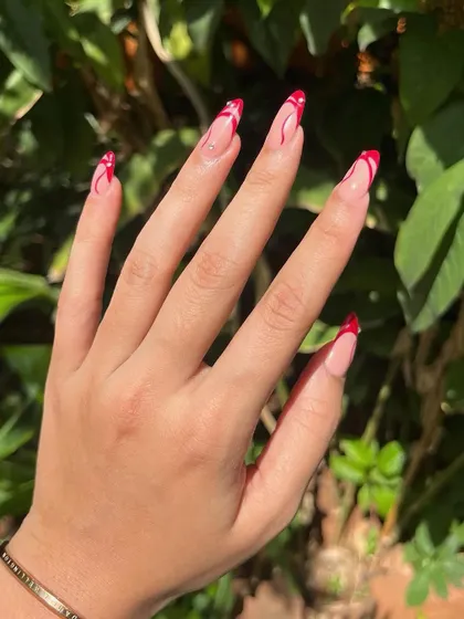 A full hand view of this trendy red swirl design on long almond-shaped extensions.