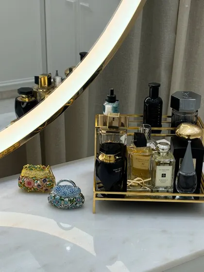 An elegant arrangement on a vanity top. A golden tray corrals perfumes, while miniature decorative bags add a touch of personal style.