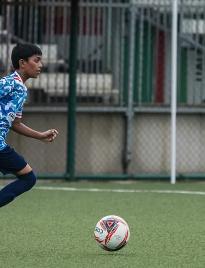 A young player from our U13 team dribbling the ball down the field during a youth league match. We train our players to be confident on the ball.