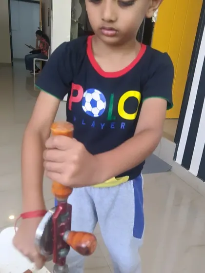 A young "polo player" takes a break from the field to learn some engineering skills with a hand drill.