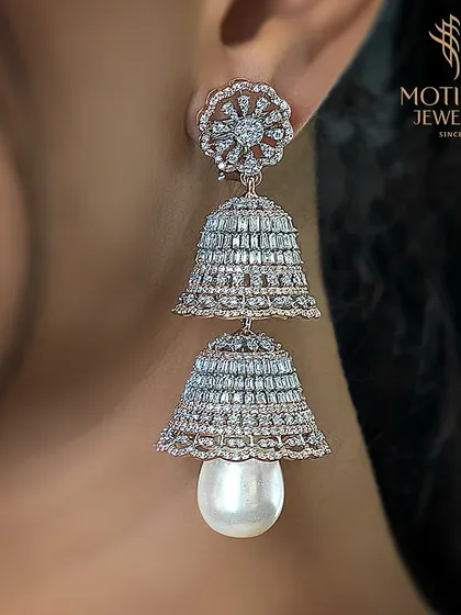 A modern interpretation of the classic jhumka, these earrings feature two tiers of baguette diamonds and a lustrous pearl drop. The design is both architectural and incredibly glamorous.