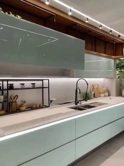 This kitchen uses a soft, minty green for its handleless cabinets, creating a very calming and modern aesthetic. The open shelving and warm under-cabinet lighting add to the cozy feel.